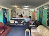 Inside The Adventure Lodge Taranna showing the shared lounge and kitchen area with dining space and seating for guests.