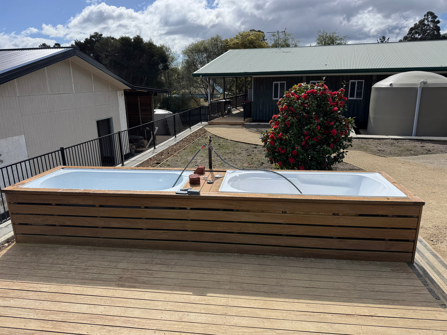 Outdoor gear wash deck at The Adventure Lodge Taranna featuring two bathtubs for rinsing and cleaning dive equipment.